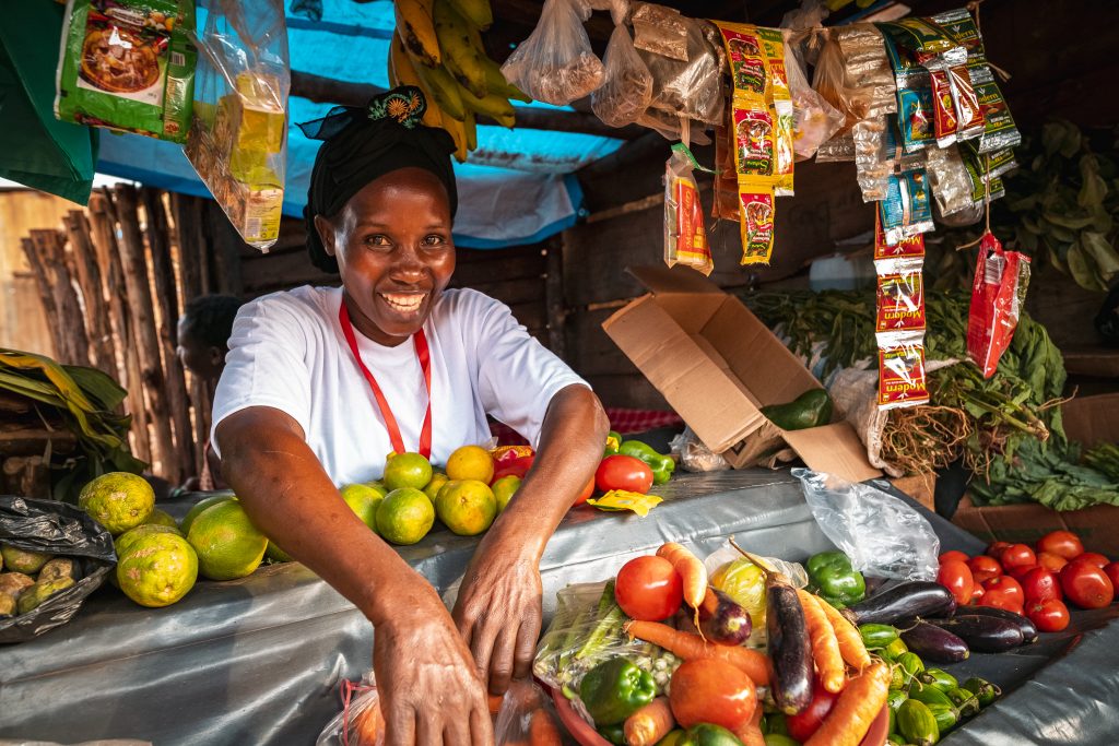 A smiling woman in her stall selling vegetables