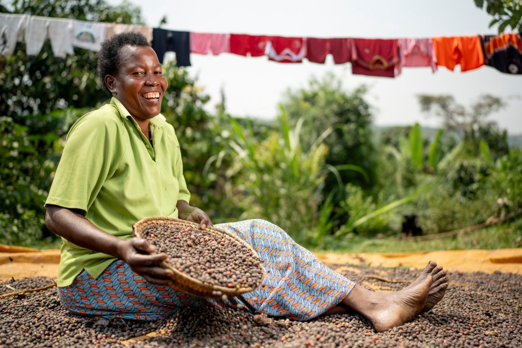 A woman sitting down holding a basket with coffee beans