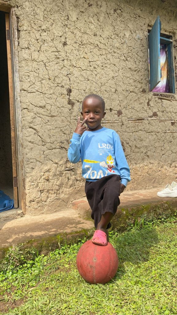 A boy standing with his right foot on top of a ball.