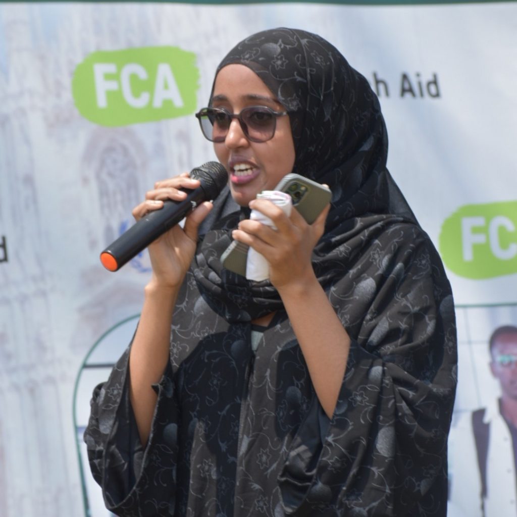 A woman wearing a black dress speaking into a microphone