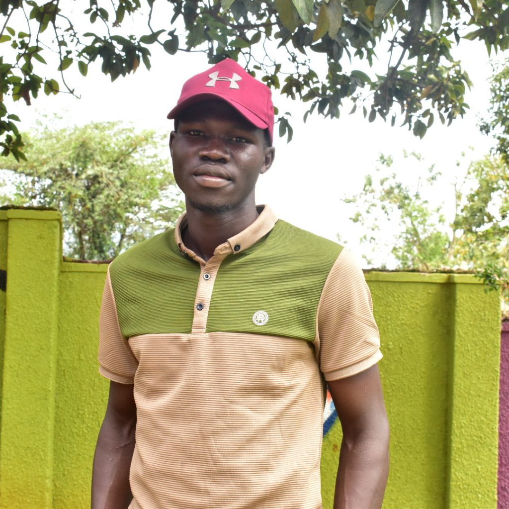 A man wearing a cap standing infront of a wall